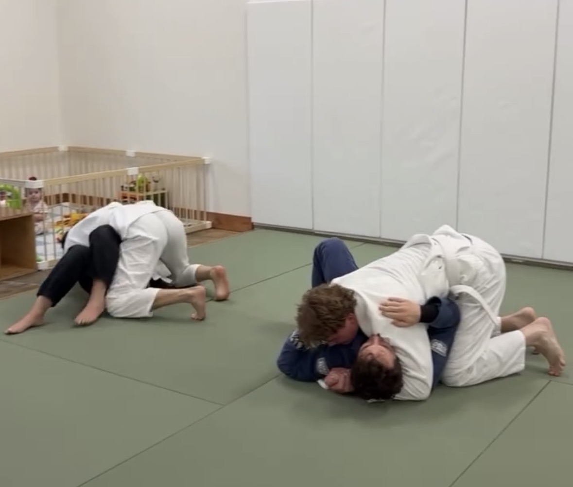 Students in Gi drilling and rolling on the mats during an open mat session at Makoto Jiu Jitsu Academy