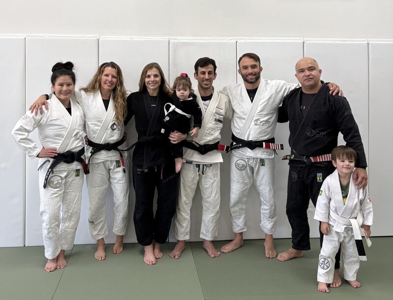 Students and families posing together on the academy mats