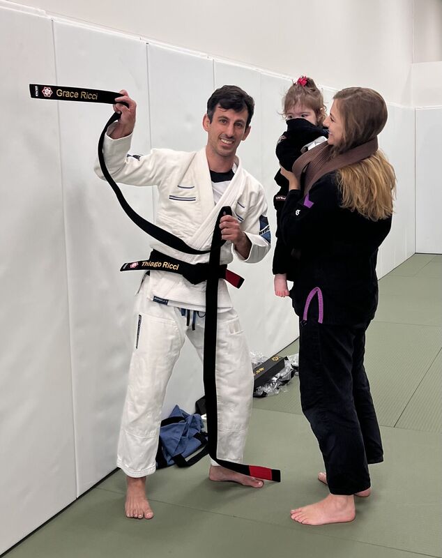 Instructor holding a belt beside a student and child