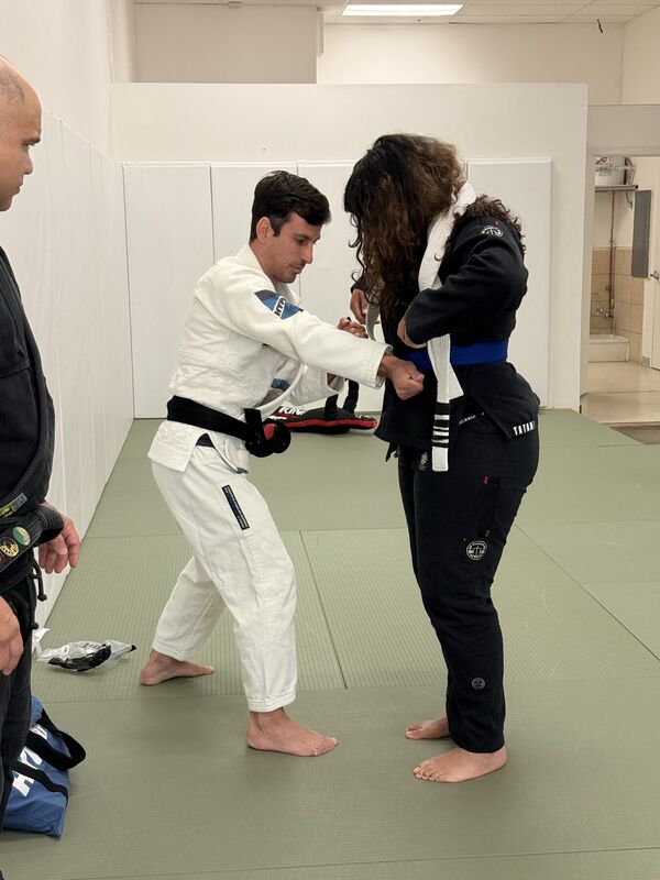 Instructor tying a belt around a student in a black Gi