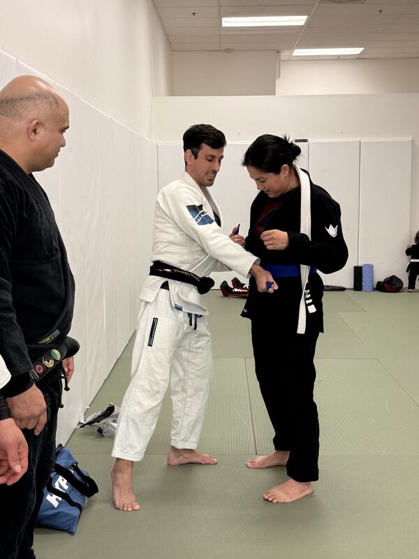 Instructor presenting a belt to a student in a black Gi